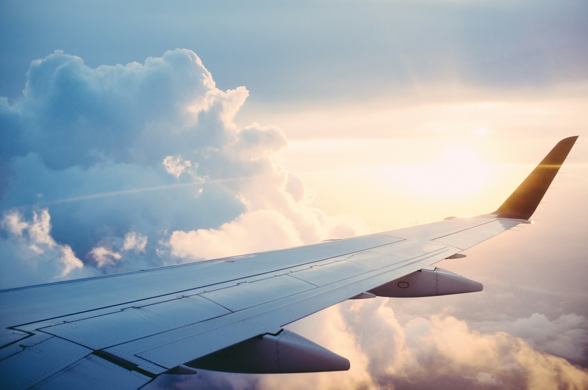 Commercial aircraft wing above the clouds at sunrise
